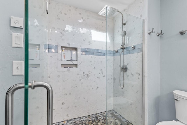 bathroom featuring toilet and a shower with shower door