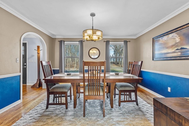 dining space with light hardwood / wood-style floors, an inviting chandelier, and ornamental molding