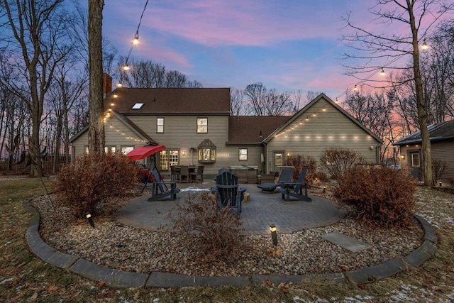 back house at dusk featuring a patio area and a fire pit