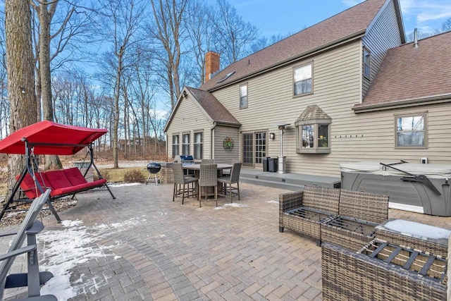 back of property featuring outdoor lounge area, a hot tub, and a patio area