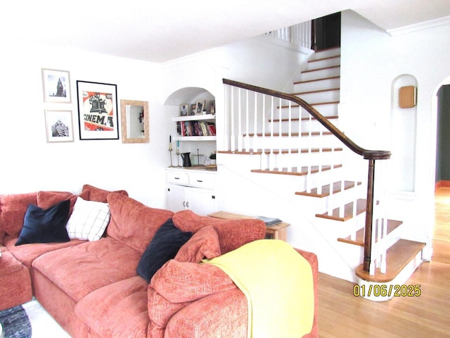 living room featuring light hardwood / wood-style floors, built in features, and crown molding