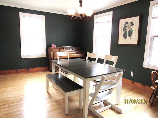 dining space with a wealth of natural light, crown molding, light hardwood / wood-style floors, and an inviting chandelier