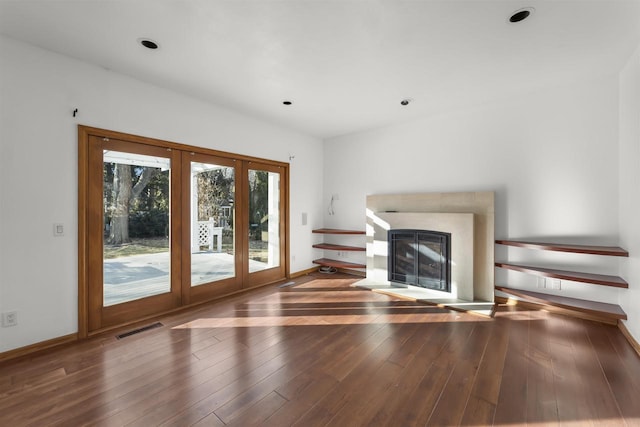 unfurnished living room with dark wood-type flooring, a high end fireplace, and french doors