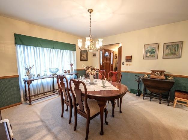 carpeted dining space with a chandelier