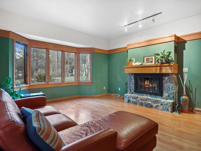 living room with a fireplace, rail lighting, and hardwood / wood-style floors