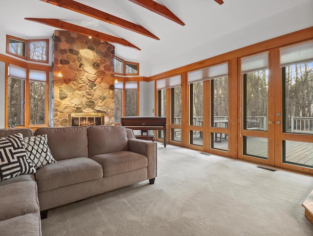 living room featuring beamed ceiling, a stone fireplace, light carpet, and high vaulted ceiling