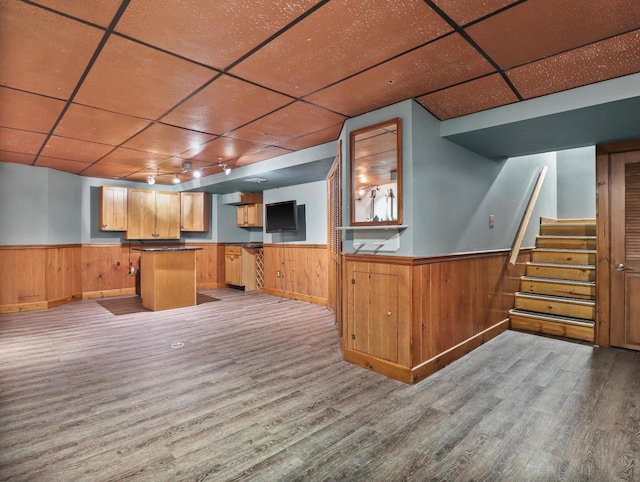 bar with wood walls, a drop ceiling, and light hardwood / wood-style floors