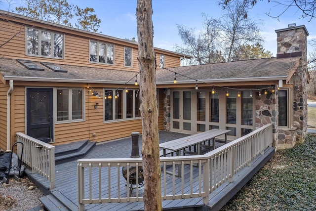 rear view of property with a sunroom and a deck