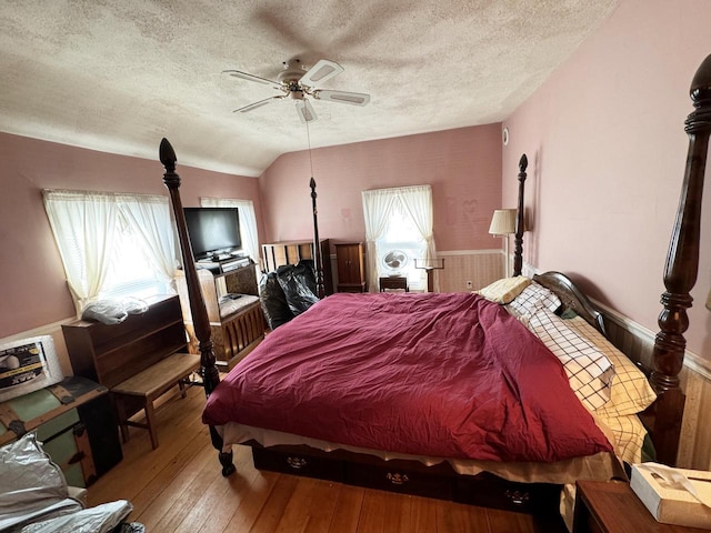 bedroom featuring a textured ceiling, hardwood / wood-style flooring, vaulted ceiling, and ceiling fan