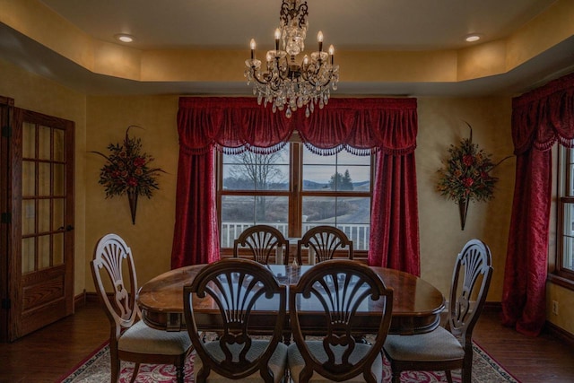 dining area with a notable chandelier, dark hardwood / wood-style flooring, and a tray ceiling