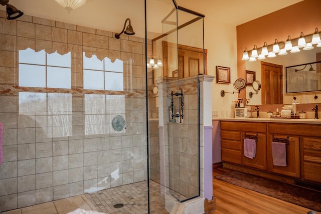 bathroom with a tile shower, vanity, and wood-type flooring