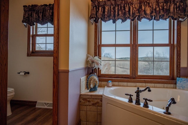 bathroom with a bathing tub, toilet, hardwood / wood-style floors, and a wealth of natural light