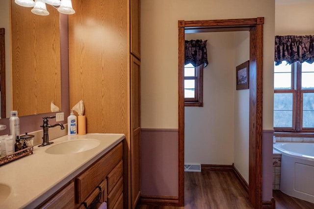 bathroom with a wealth of natural light, a bathtub, vanity, and hardwood / wood-style floors