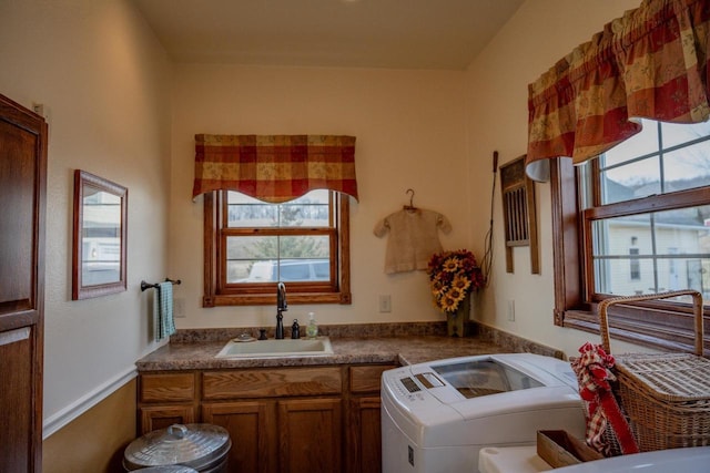 washroom with cabinets, washing machine and dryer, a healthy amount of sunlight, and sink