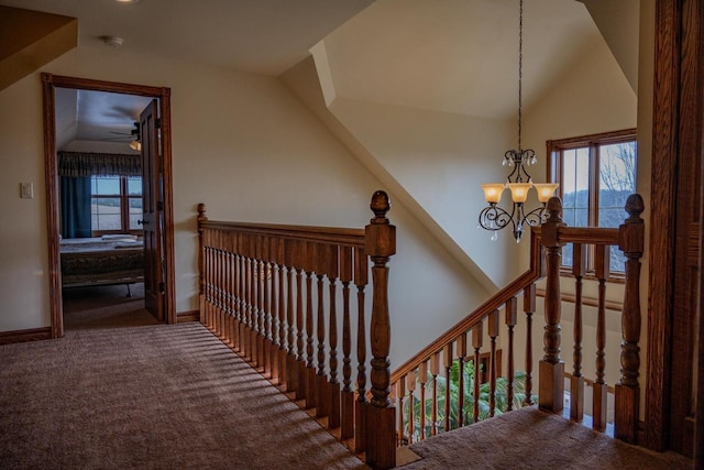 staircase featuring ceiling fan with notable chandelier, carpet floors, and lofted ceiling