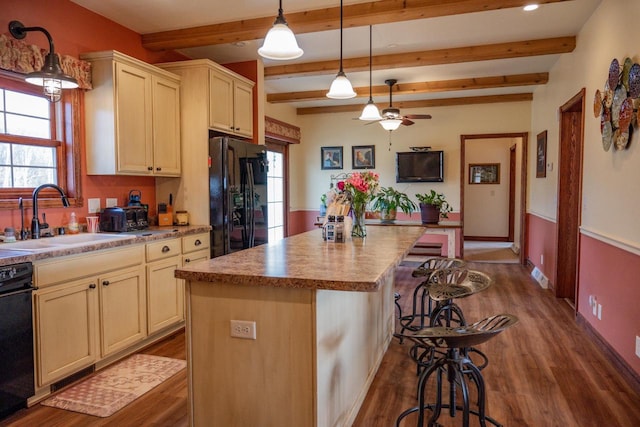 kitchen featuring sink, black appliances, beam ceiling, a kitchen island, and hanging light fixtures