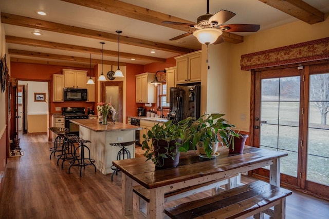 kitchen featuring pendant lighting, a kitchen island, black appliances, and beamed ceiling