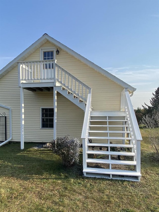 rear view of property featuring a balcony and a yard