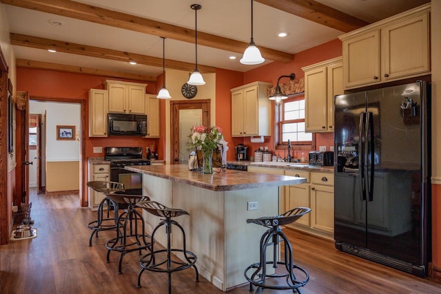 kitchen with a breakfast bar, black appliances, beam ceiling, pendant lighting, and a kitchen island