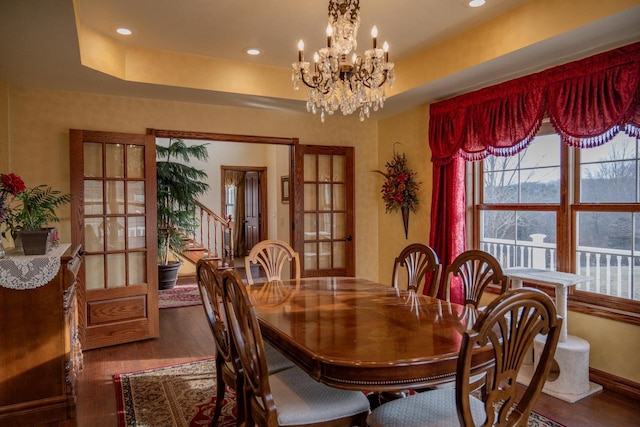 dining room with dark hardwood / wood-style flooring, a raised ceiling, a chandelier, and french doors