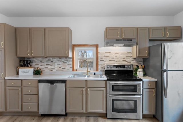 kitchen featuring appliances with stainless steel finishes, light wood-type flooring, tasteful backsplash, and sink