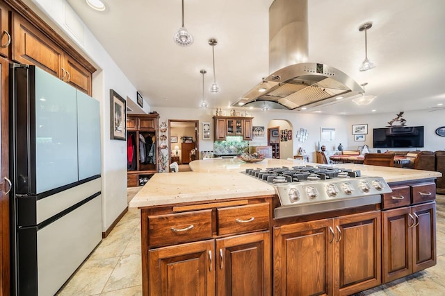 kitchen featuring stainless steel gas stovetop, island range hood, hanging light fixtures, a kitchen island, and white fridge