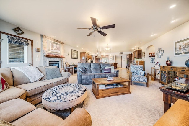 living room featuring ceiling fan, light colored carpet, and a fireplace