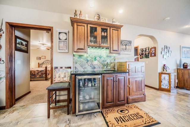 bar featuring decorative backsplash, light colored carpet, beverage cooler, ceiling fan, and sink