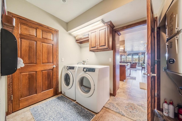 laundry area with cabinets, light tile patterned floors, and washing machine and clothes dryer