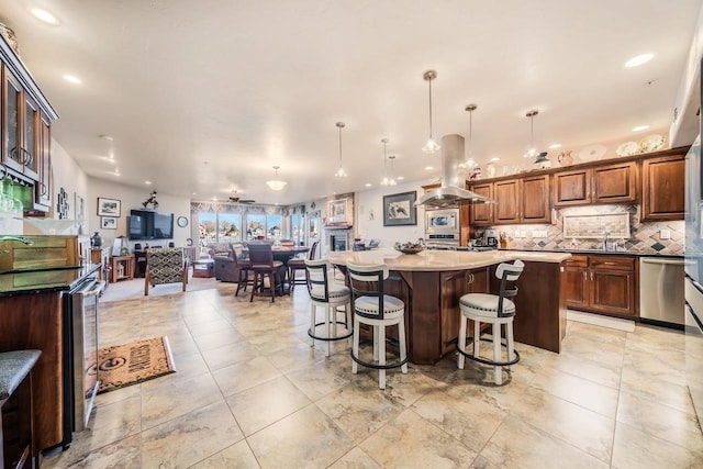 kitchen featuring hanging light fixtures, a breakfast bar area, stainless steel dishwasher, a kitchen island, and island exhaust hood