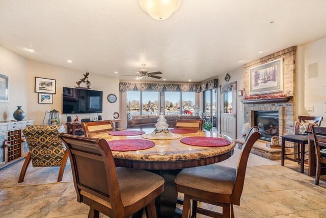 dining area with ceiling fan and a large fireplace