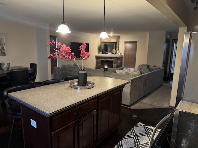 kitchen with hanging light fixtures, a kitchen breakfast bar, a fireplace, a kitchen island, and range