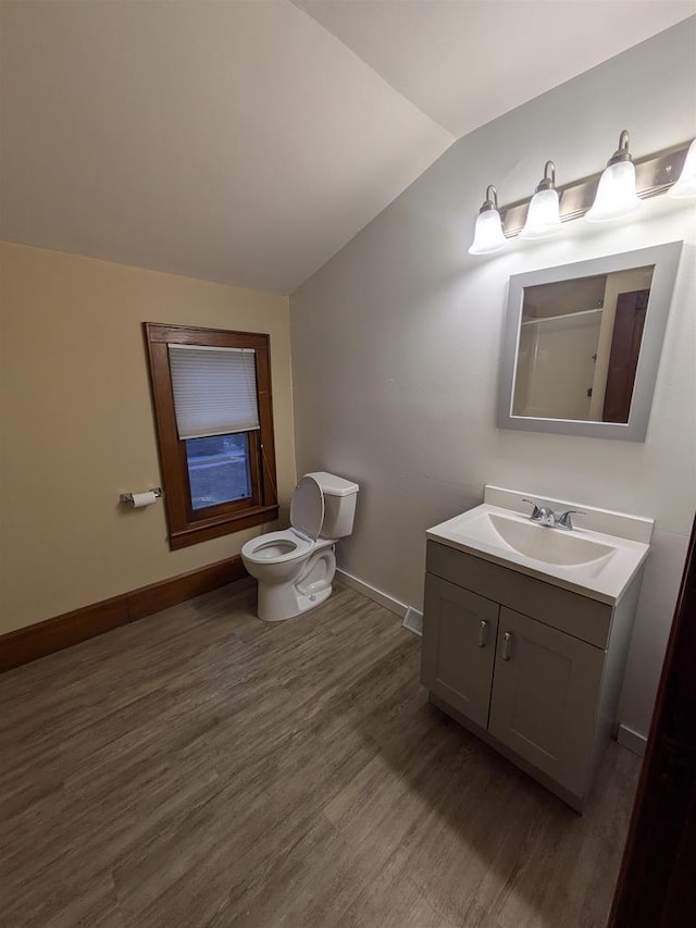 bathroom with vanity, toilet, lofted ceiling, and wood-type flooring