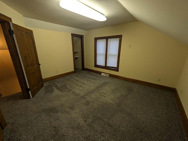 interior space featuring dark carpet and lofted ceiling