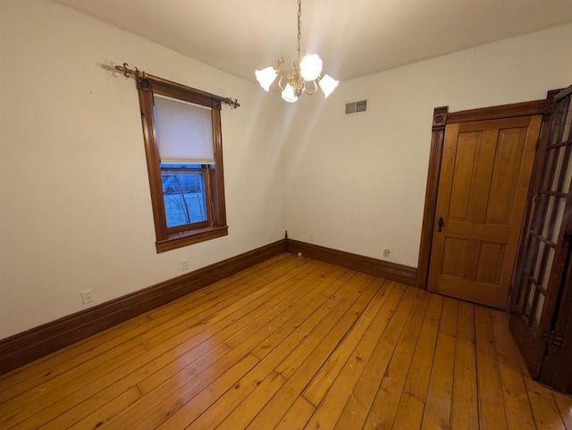 empty room featuring light hardwood / wood-style floors and an inviting chandelier