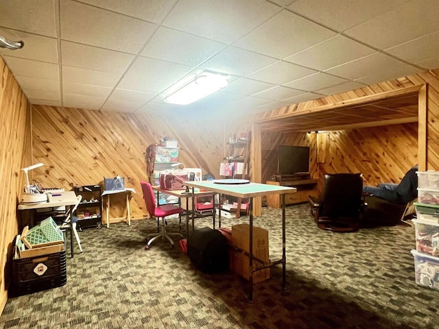 rec room with a paneled ceiling, wooden walls, and carpet