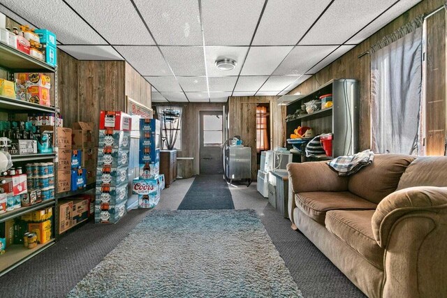 interior space featuring dark carpet, a drop ceiling, and wood walls