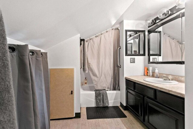 bathroom with wood-type flooring, vanity, and shower / tub combo with curtain