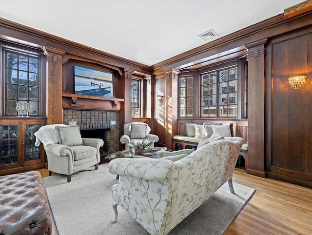 sitting room with a fireplace, light wood-type flooring, crown molding, and wood walls