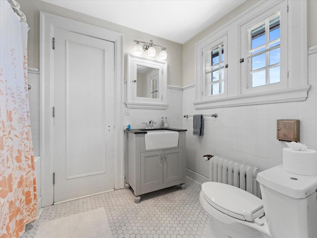 bathroom with tile patterned floors, vanity, tile walls, radiator heating unit, and toilet