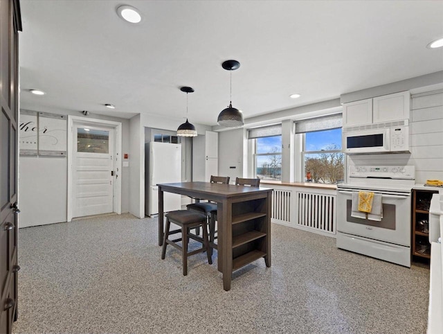 kitchen featuring white cabinets, decorative light fixtures, and white appliances