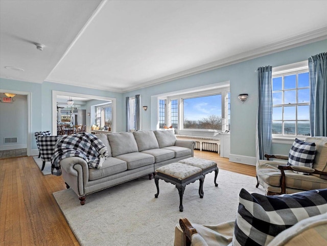 living room featuring radiator, ornamental molding, ceiling fan, a water view, and light hardwood / wood-style floors