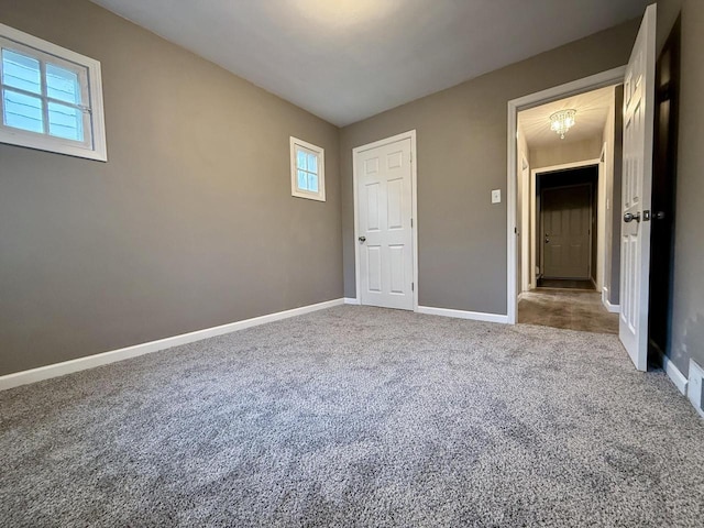 unfurnished bedroom with carpet and an inviting chandelier