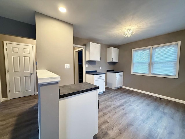 kitchen with dark hardwood / wood-style flooring, white cabinets, and a notable chandelier