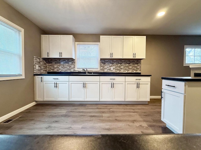 kitchen with tasteful backsplash, white cabinetry, and light hardwood / wood-style floors