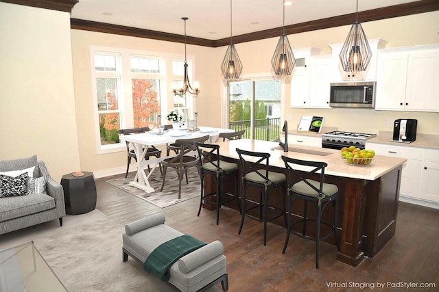 kitchen featuring a center island with sink, decorative light fixtures, white cabinetry, and range