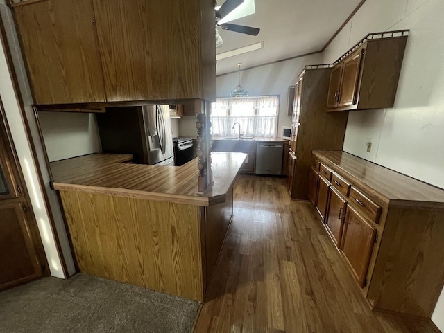 kitchen with appliances with stainless steel finishes, vaulted ceiling, ceiling fan, dark wood-type flooring, and sink