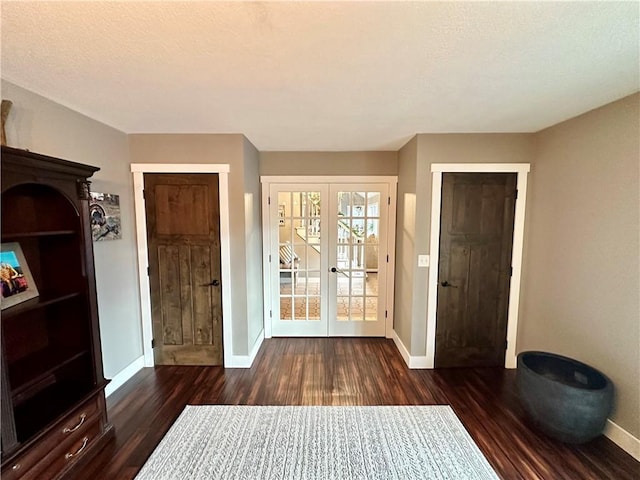 doorway with a textured ceiling, dark wood-type flooring, and french doors