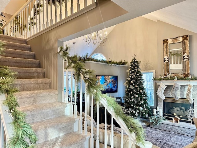 stairway featuring a high end fireplace, high vaulted ceiling, and an inviting chandelier