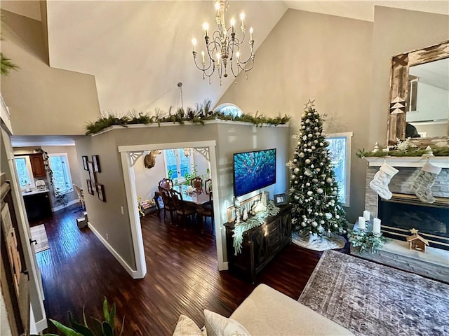 living room featuring a fireplace, high vaulted ceiling, dark hardwood / wood-style floors, and an inviting chandelier